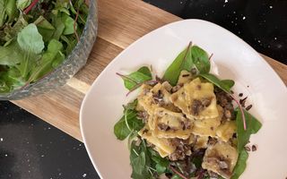 Bord met een pastagerecht, opgediend op een bedje van sla.