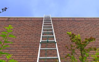 Een hoge ladder staat tegen een hoge muur
