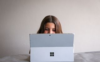 Meisje met bruin haar achter grijze tablet.