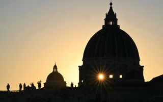 De zon gaat onder achter een grote koepel van een kerk.