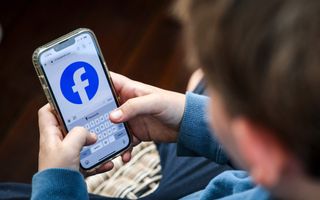 Tiener heeft mobiele telefoon in handen met afbeelding van sociale media.