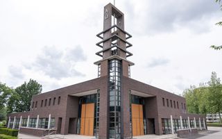 Modern, rechthoekig kerkgebouw, met toren. Op de toren de Griekse letters Alpha en Omega.