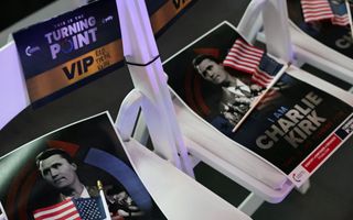 Close-up van witte klapstoelen met daaromheen een flyer met een portret van de overleden Charlie Kirk.