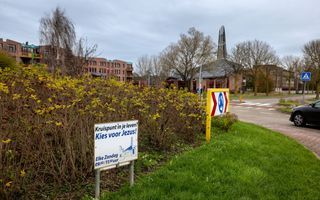 Een bord met de tekst ”Kruispunt in je leven? Kies voor Jezus!” op een rotonde in Zwolle. Op de achtergrond staat een kerkgebouw.