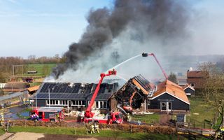 Vanuit hoogwerkers blust de brandweer een brand in een zorgboerderij. 