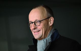 Man met bril, zwarte jas en grijze sjaal 