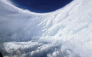 Een  halfronde muur van lichte wolken. Daarboven een donkerblauwe lucht.