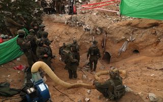 Gewapende militairen in groen uniform staan bij ingang van een tunnel. 