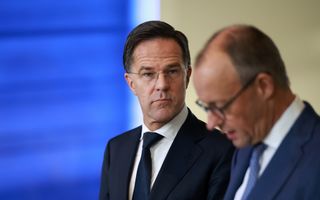 Man in pak, Mark Rutte, kijkt somber naar een andere man in pak, Merz.