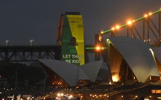 Een groen-gele reclameprojectie op de brug in donker Sydney