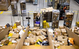 Medewerkers laden gesorteerde pakketen in containers in een sorteercentrum van bezorgdienst DHL. 