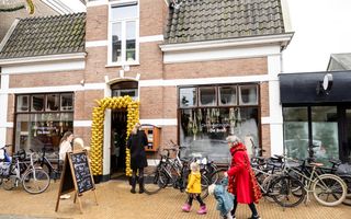 Historisch pand in een dorpsstraat met op de ruit de woorden Ontmoetingshuis De Bron. Om de ingang zijn goudkleurige ballons bevestigd.