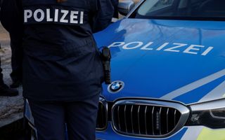 Een politieauto met een politieman ervoor.