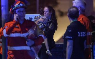 Vrouw houdt kind, dat in isolatiedeken is gewikkeld, in haar armen,