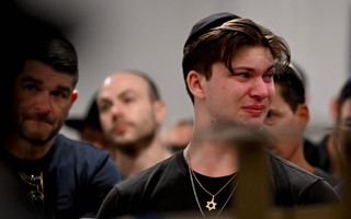 Jongeman met een keppeltje probeert zijn emoties te bedwingen. Om zijn nek hangt een goudkleurige ketting met daaraan een Davidsster.