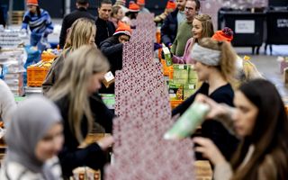Mensen zijn bezig met het inpakken van dozen. Daarin worden voedingsmiddelen gestopt. Enkele vrouwen dragen een hoofddoek.