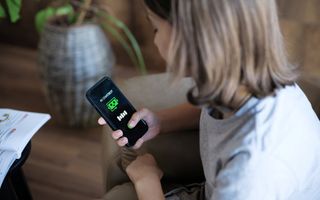 Meisje met bruin halflang haar kijkt op haar telefoon naar een chatbot.