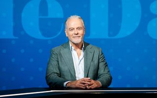 Glimlachende man met korte baard en groen colbertje.