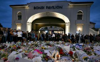 Bloemenzee met mer erachter mensen. Op de achtergrond een gebouw met de naam Bondi Pavilion.