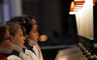 Kinderen in witte koorkleding zingen.