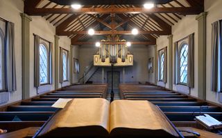 Vergeelde kanselbijbel, twee rijen banken. Het pijporgel zit achter een dakspant.