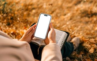 Een jongere houdt een smartphone vast en heeft een Bijbel op schoot.