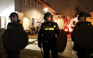 Drie ME’ers staan op een rij. Op de achtergrond een brandweerwagen