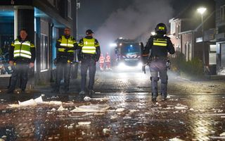 Politieagenten staan op de voorgrond en brandweerauto met brandweerlieden op de achtergrond.