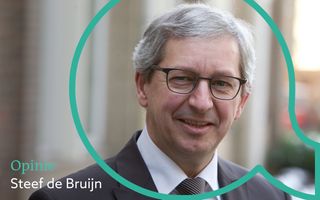 Vignet Toegespitst, met een lachende oudere man, bril, grijs haar, in pak.