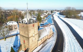 Oude kerk langs een dijk, in besneeuwd landschap.
