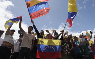 Venezolanen met geel-blauw-rode vlaggen vieren feest op straat.