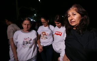 Vrouwen houden elkaars hand vast en staan met de ogen dicht.