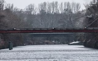 Brug over water in winterlandschap.
