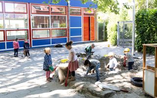 Kinderen spelen op een schoolplein en in een zandbak.