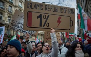 Vrouw houdt een kartonnen bord omhoog met daarop een batterij getekend. 