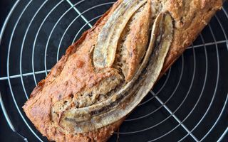 Cake met bovenop twee halve bananen op een rond metalen rooster.