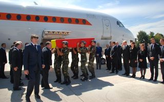 Militairen dragen kist die bedekt is met rood doek.