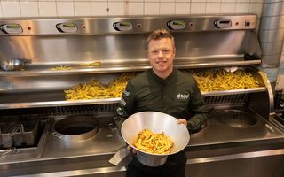 Man met schaal friet voor professionele friteuse.