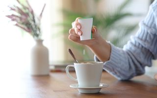 Een vrouw doet zoetstof in haar koffie. 