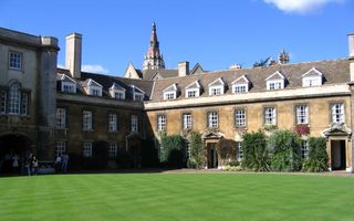 Oude gebouwen rondom een grasveld.