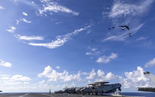 Vliegtuigen staan op vliegdekschip dat op zee vaart.