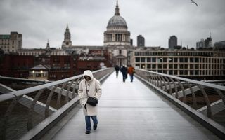 Mensen lopen over een brug in Londen. Op de achtergrond St. Paul’s Cathedral.