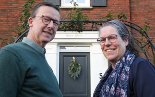 Een man en een vrouw voor een huis met een voordeur waarboven staat: Repos Ailleurs.