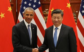 Obama en Xi Jinping schudden elkaar de hand voor de vlaggen van beide landen.