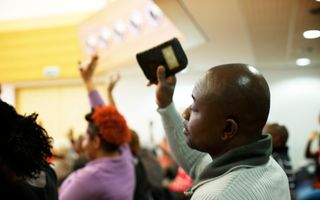 Man bidt met opgeheven hand in migrantenkerk.