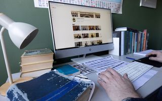 Man zit achter een bureau met daarop een computerscherm te werken. Een YouTubepagina met preekvideo’s staat open op het scherm.