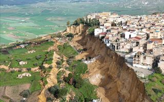 Luchtfoto van een aardverschuiving bij Niscemi, waarbij grote stroken aarde en vegetatie zijn weggegleden.