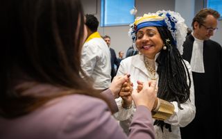 Een getinte vrouw met donker haar in traditionele kleding lacht hard.