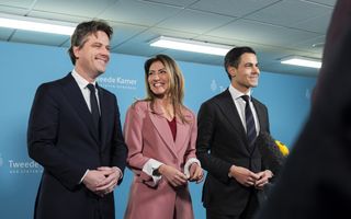 Drie lachende mensen tegen een blauwe achtergrond met daarop logo’s van de Tweede Kamer.