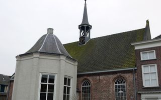 Oud bakstenen kerkgebouw, met witgeschilderde uitbouw.